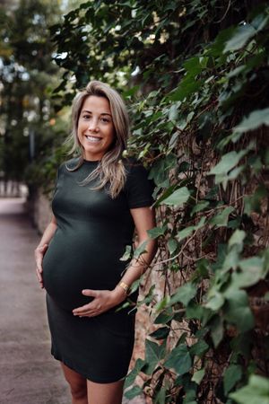 Charming pregnant woman standing on walkway in park