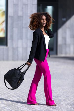 Female in bright pink trousers and handbag walking outside