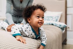 Happy baby boy crawling on bed