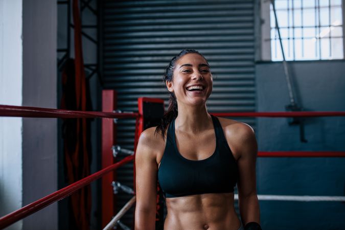 Smiling fit female boxer leaning in the ring