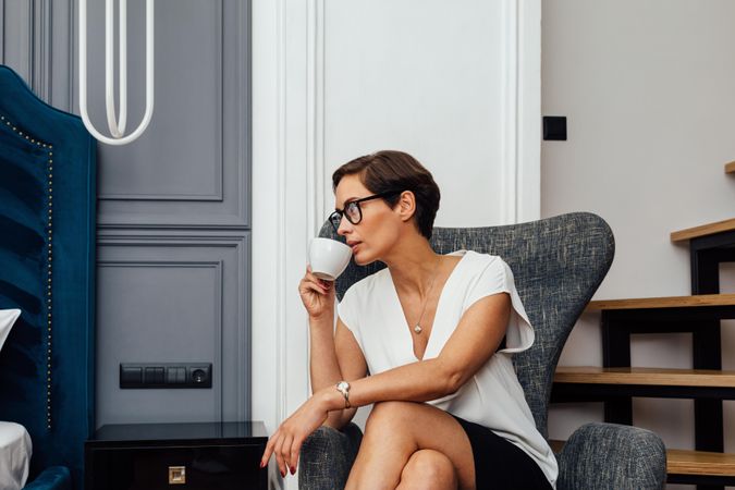 Woman looking away sitting near stairs with a coffee