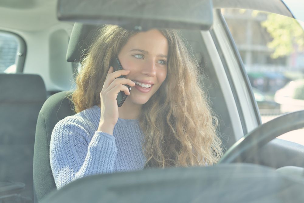 Smiling woman talking on smartphone in car