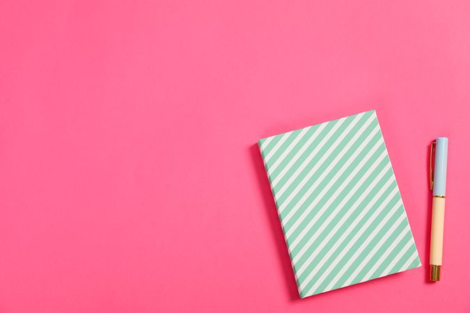 Copybook and pen on pink background, space for text