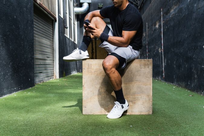 Anonymous fit man browsing smartphone during training