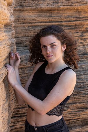 Young female leaning on sandstone rock