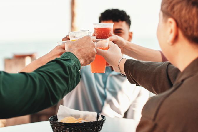 Friends Cheers with Colorful Drinks by the Sea