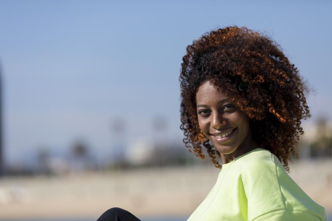 Confident female sitting near beach in bright green shirt