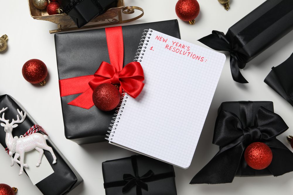 Gift boxes, decorations and notepad with text on light background, top view