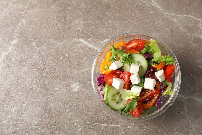 Glass bowl with fresh salad on grey background, copy space