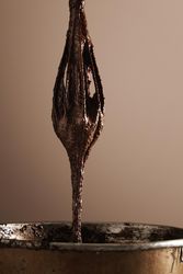 Whisk emerging from steel bowl with melted chocolate