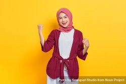 Woman in red headscarf with both arms up in victory 486zY0