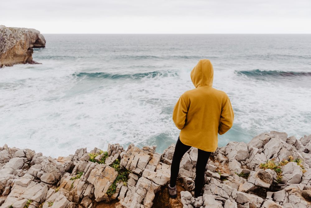 Person in yellow hoodie on stony shore