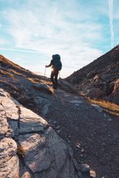 Back view of man with backpack hiking in Switzerland natural landscape at sunrise