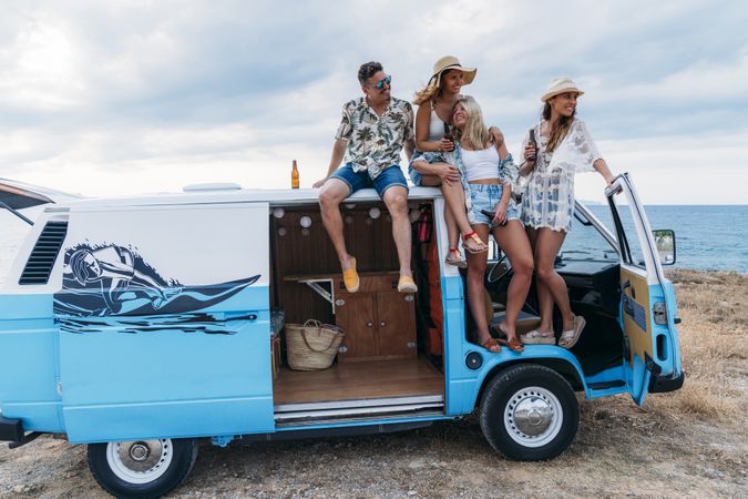 Relaxed friends comfortable placing on top of blue car