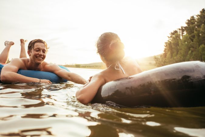 Affectionate young couple floating on innertubes in water