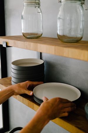 Person placing ceramic bowl on shelf in shop