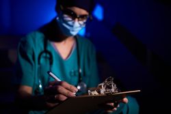 Focused female doctor writing medical report in darkness