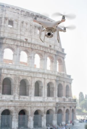 Unmanned Aircraft System Quadcopter Drone UAV In The Air Near The Colosseum In Rome.