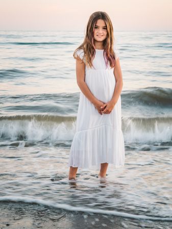 Smiling girl standing on seaside among waves