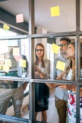 Business people in a work meeting placing sticky notes on the wall