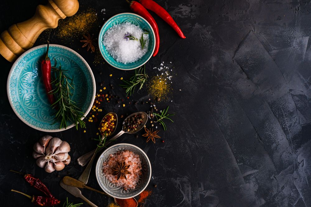 Spices, herbs and salt on dark counter with copy space