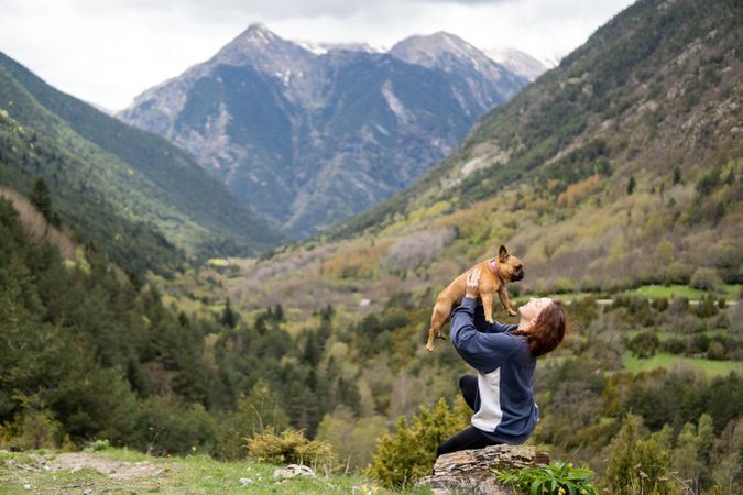 Happy traveling woman with cute dog in highlands