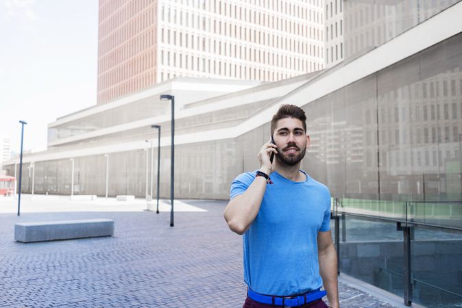 Portrait of young man speaking on phone while walking outdoors