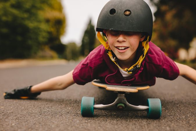 Funny boy with helmet lying on skateboard