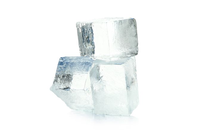 Three angular clear ice cubes in bright room