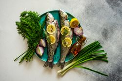 Trout fish ready for cooking surrounded by vegetables