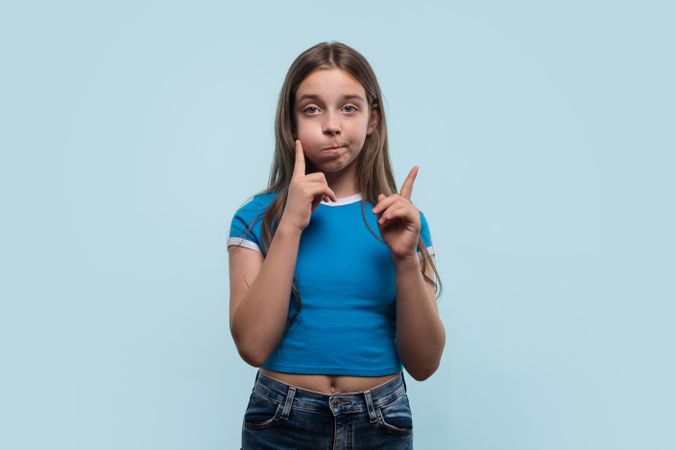 Young girl gestures thoughtfully, pondering decision on light background