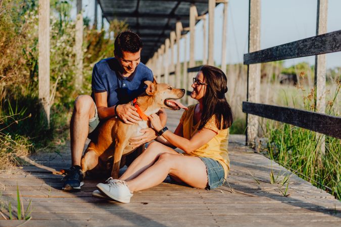 Happy adult couple having fun with dog at countryside
