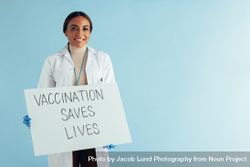 Woman doctor showing a placard against blue background 42qgK5