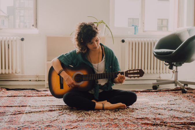 Content woman playing guitar at home