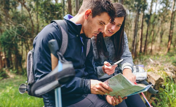 Couple doing trekking sitting looking mobile and map