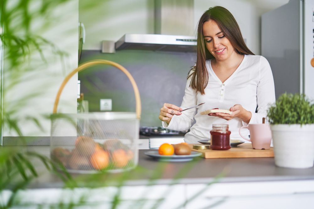 Smiling woman making sandwiches in kitchen