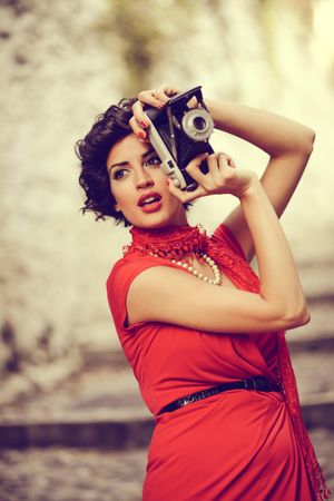 Elegant woman in dress and pearls taking a photo