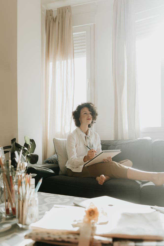 Woman writing on paper on sofa in room