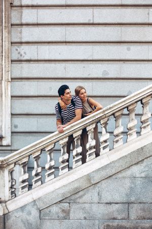 Young couple standing on ancient stairs against wall