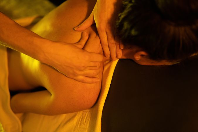 Close of up masseuse’s hands kneading client’s back
