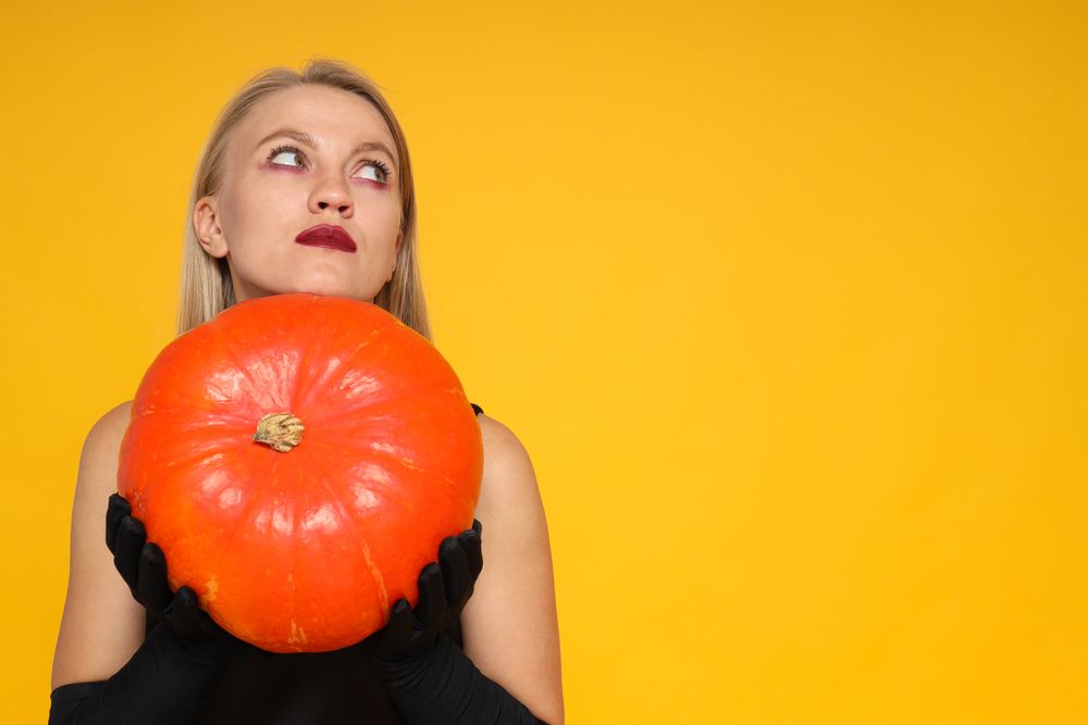 A woman in a Halloween outfit with a pumpkin in her hands