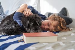Preteen boy sleeping on bed with dog