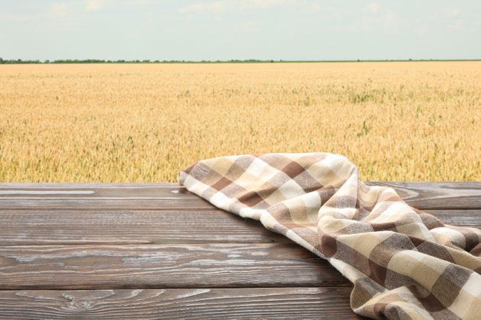 Wooden table with towel against field. Agriculture concept