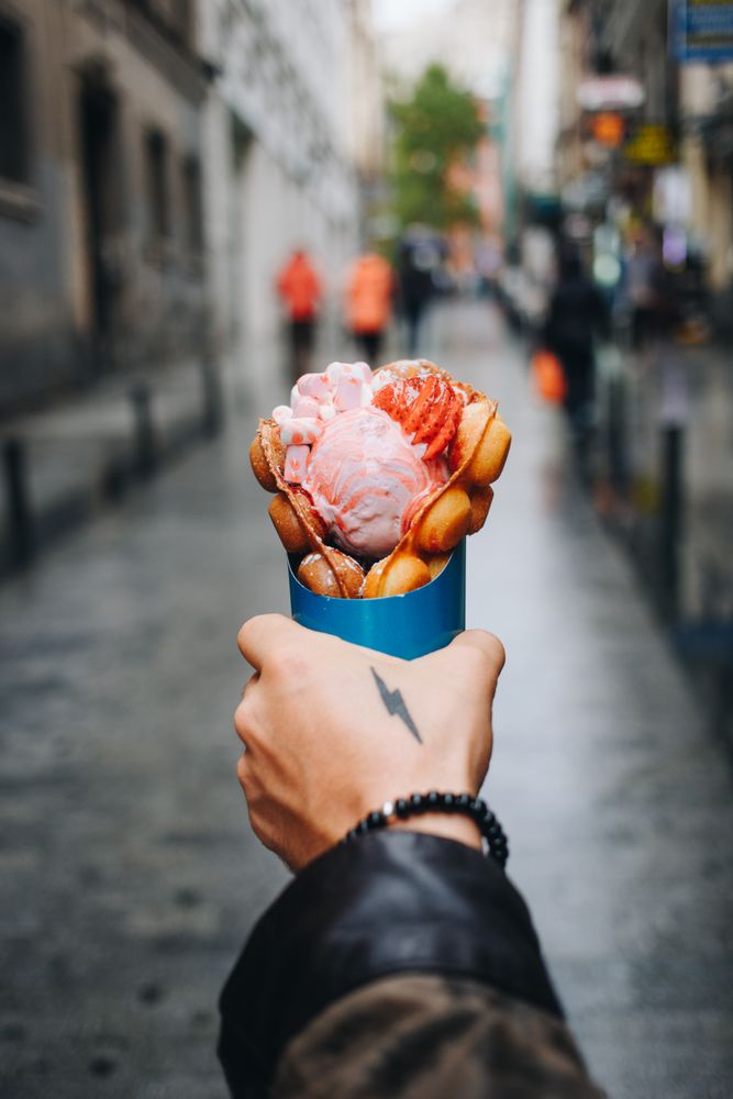 Tattooed hand holding waffle and ice cream dessert