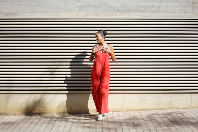 A Stylish Woman Dressed in a Vibrant Red Dress Posing in Front of a Textured Wall