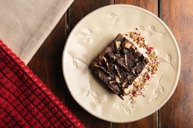 Tasty brown cake decorated with flakes on plate
