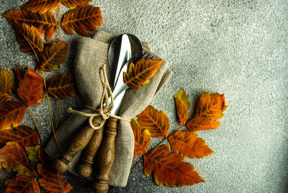 Autumnal table setting with bright yellow leaves on stone background with copy space