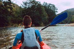 Female kayaking with paddle in raised hands