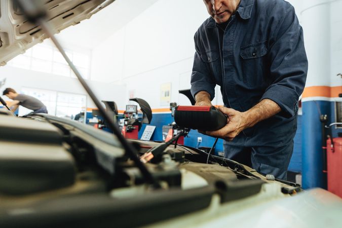 Mechanic using a device to check the engine