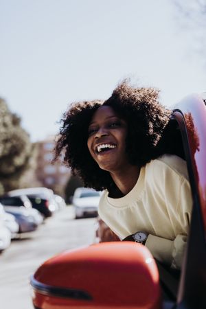 Female with afro hair peeking out of the car .